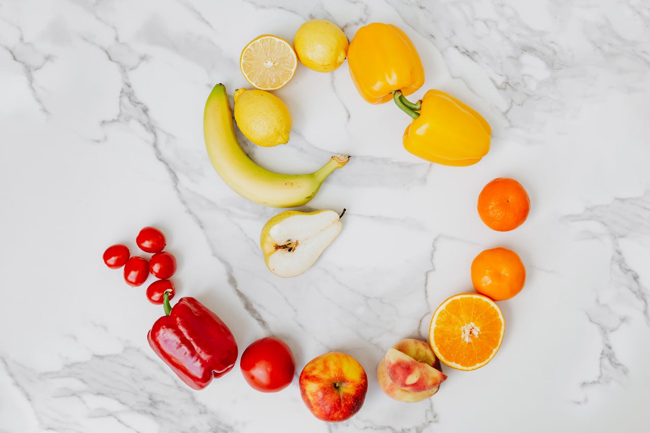 Vibrant top view of assorted fruits and vegetables arranged in a circle on a marble surface.