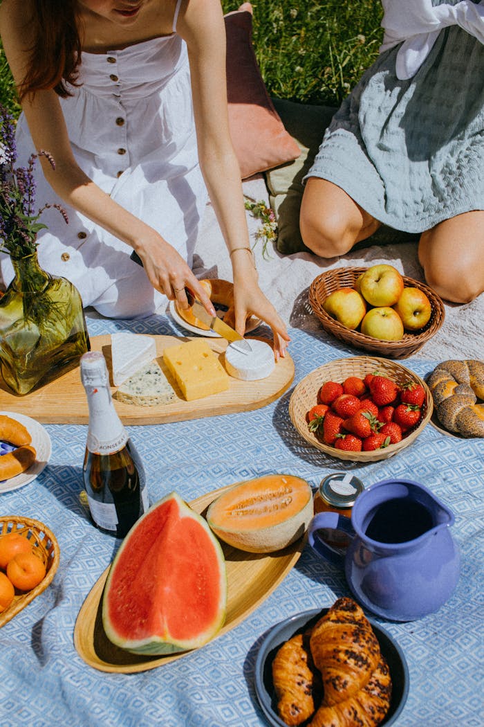 Relaxing outdoor picnic with a variety of fruits and cheese on a sunny day.