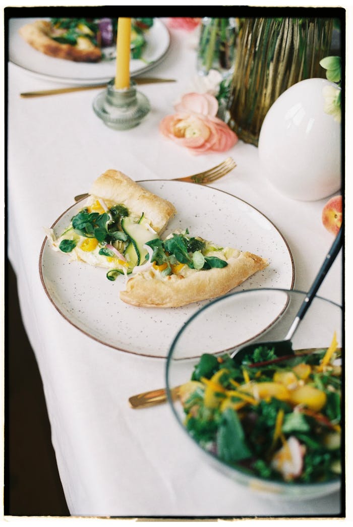 Delicious gourmet vegetable pizza served with a fresh salad on an elegant table setting.